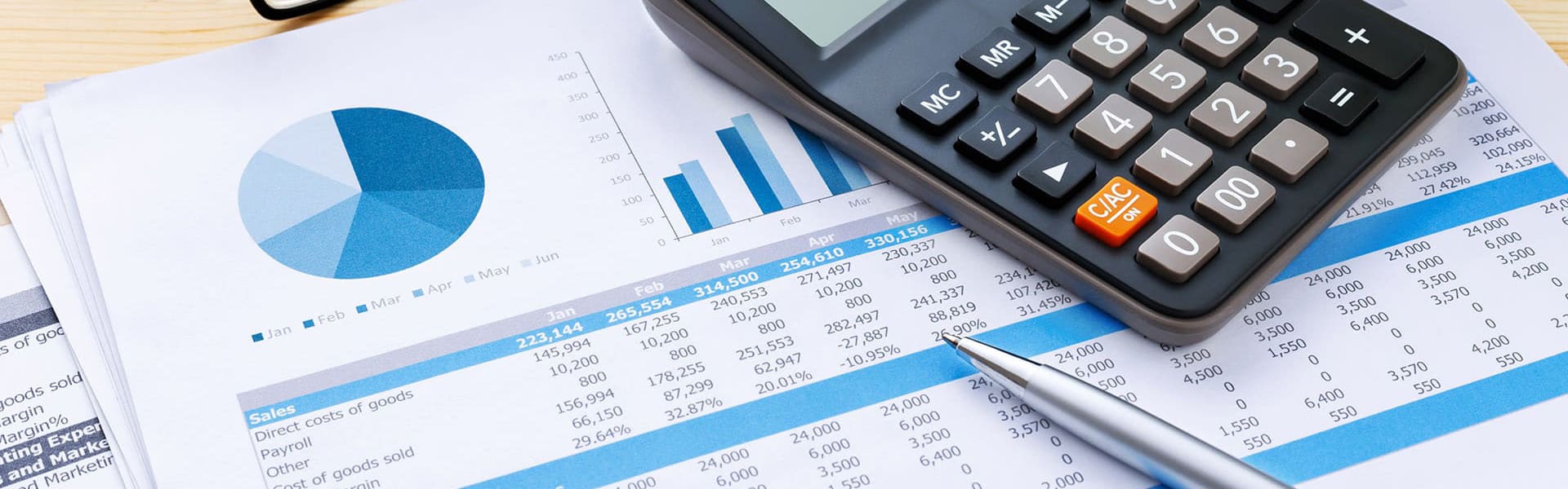 The image features a business financial report along with a calculator and a pen, suggesting a scenario of financial analysis or accounting. It visually represents typical tools and documents used in financial planning, auditing, or budgeting in a corporate environment. The visible charts and numerical data highlight the detailed tracking of business performance over time.
